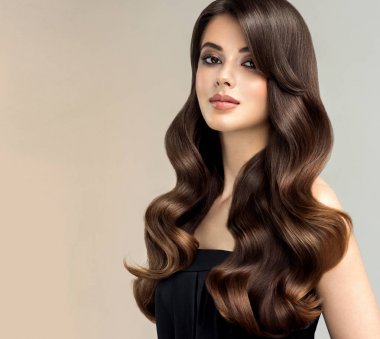 Uzun, sağlıklı ve parlak kıvırcık saçlı esmer kız. Güzel model kadınla dalgalı saç modeli. Bakım ve güzellik