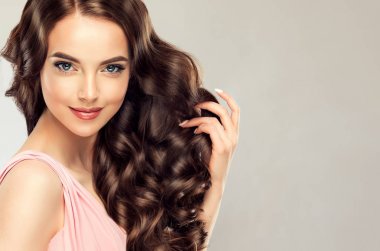 Uzun, sağlıklı ve parlak kıvırcık saçlı esmer kız. Güzel model kadınla dalgalı saç modeli. Bakım ve güzellik