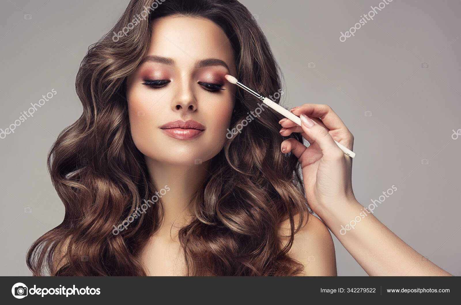 Makeup artist applies eye shadow . Beautiful woman with make-up face. Hand  of visagiste, painting cosmetics of young beauty model girl . Make up in  process Photos