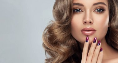Uzun kıvırcık saçlı, güzel bir manken. Moda modası imajı, tırnaklarında manikür olan kız. Kozmetik, makyaj ve dalgalı saç stili