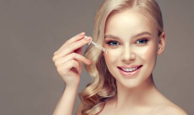 Skin care concept. Beauty portrait of smiling young woman girl holding pipette with cosmetic oil or serum near clean face. Cosmetology and Spa clipart