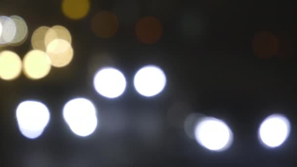 Luces de tráfico desenfocadas de la ciudad nocturna. Color Bokeh borroso de transporte en movimiento y ruido típico de la ciudad . — Vídeos de Stock