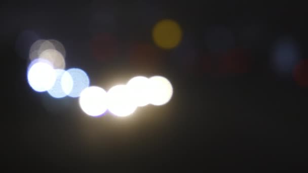 Luces de tráfico desenfocadas de la ciudad nocturna. Color Bokeh borroso de transporte en movimiento y ruido típico de la ciudad . — Vídeos de Stock