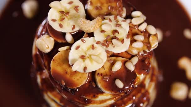 Frittelle con sciroppo di cioccolato, noci e banane. Una pila di patatine intere. Colazione gustosa e cibo sano — Video Stock