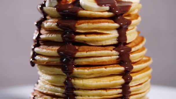 Frittelle con sciroppo di cioccolato, noci e banane. Una pila di patatine intere. Colazione gustosa e cibo sano — Video Stock