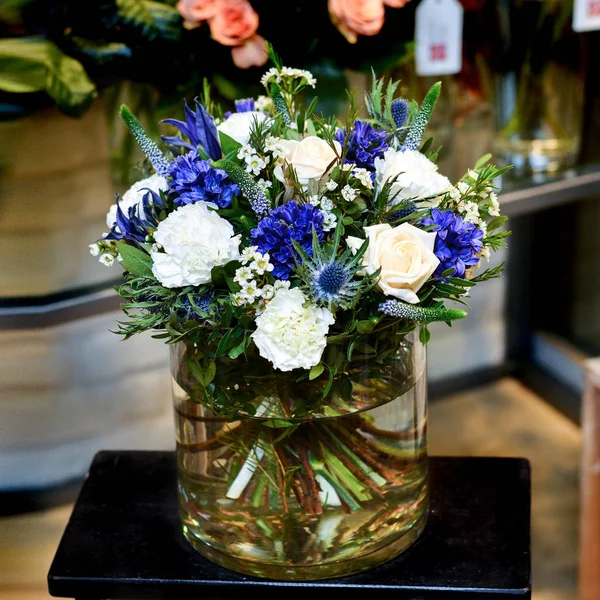 Strauß mit weißen und blauen Blumen in einer Glasvase — Stockfoto