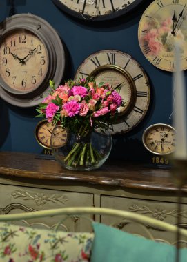 Şeffaf, yuvarlak ahşap bir masa üzerinde duran cam vazo içinde gül buketi