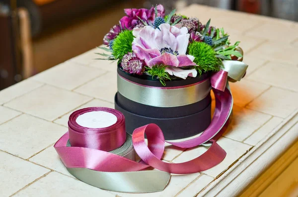 Şeritler bir kutu içinde pembe çiçekli küçük buket