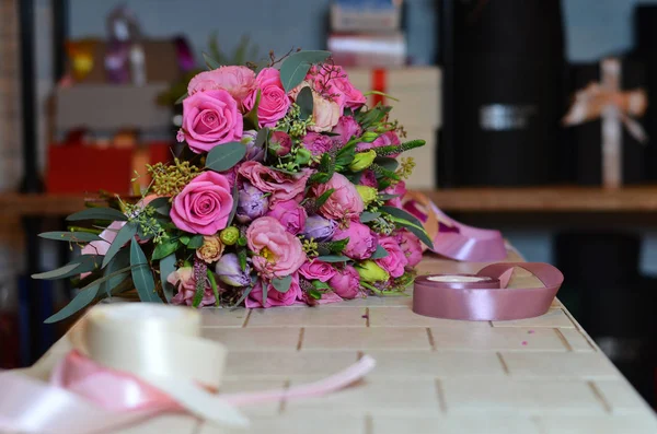 Ramo de Rosas está en la mesa junto a las cintas multicolores . — Foto de Stock