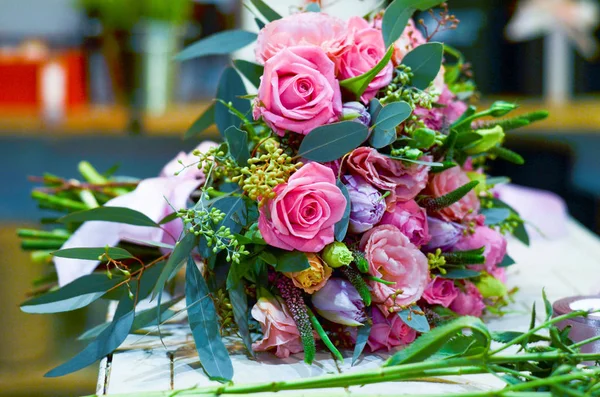 Boeket rozen is op de tafel naast de multi-gekleurde linten — Stockfoto