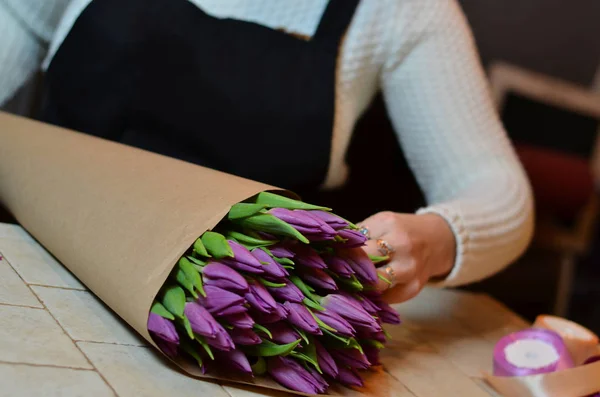 Una mujer hace un ramo de tulipanes morados. Fondo borroso . — Foto de Stock