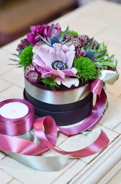 Şeritler bir kutu içinde pembe çiçekli küçük buket