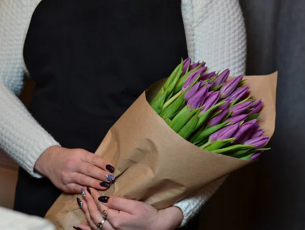 Eine Frau mit einem Bouquet von violette Tulpen, in Papier eingewickelt — Stockfoto