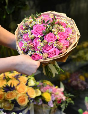 Bir buket gül tutan bir kadın kağıt sarılı