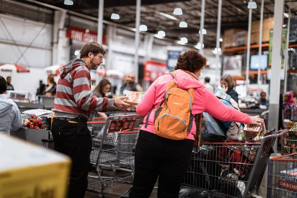 Люди с тележками в Оптовом магазине Костко. Costco - американская транснациональная корпорация, управляющая только цепочкой членства — стоковое фото