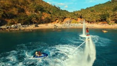 Hava: flyboard denize yakın uçan iki adam.