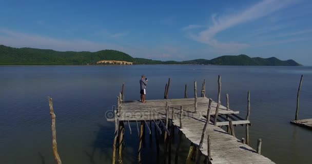 Antenne: Man regelt de drone vanaf de pier. — Stockvideo