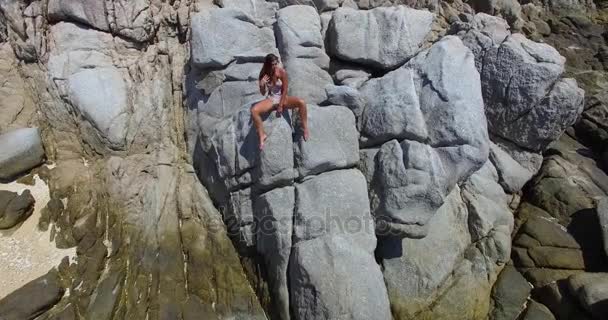 Aérea: Joven modelo posando sobre las rocas en la playa salvaje. Tailandia . — Vídeo de stock