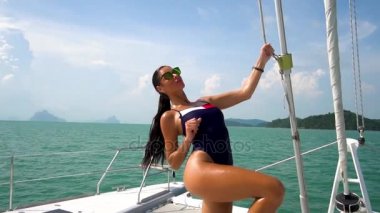 Yavaş çekimde bir yat güvertede poz güneş gözlüklü bir kız. Deniz Manzaralı.