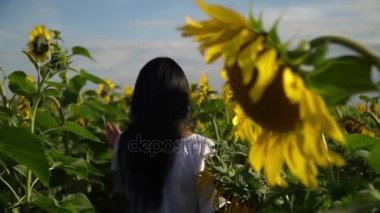 Kız alan ayçiçeği ile size yürür ve etrafına bakıyor.