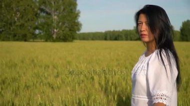 Bir kız bir buğday alanında standları ve çevresinde güzellik hayran.