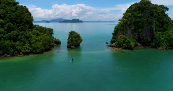Aerial: Un uomo nuota su una tavola da sup nel mare vicino alle isole . — Video Stock