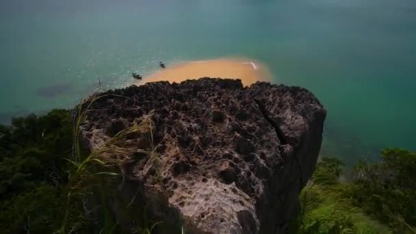 Nézd meg a tetején a szikla. Két longtail csónakok állnak a strandon. — Stock videók