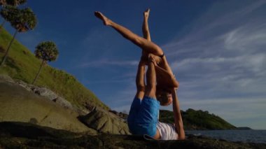 Acro Yoga kaya deniz kenarında gün batımında sahilde.