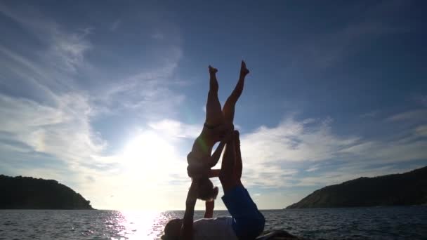 Acro Yoga στο βράχο στην παραλία το ηλιοβασίλεμα, κοντά στη θάλασσα. — Αρχείο Βίντεο