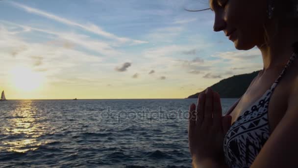 Ένα κορίτσι στέκεται στο tadasana το ηλιοβασίλεμα δίπλα στη θάλασσα. Κάνει γιόγκα. — Αρχείο Βίντεο