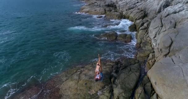 Aéreo: Acro Yoga nas rochas perto do mar e belas ondas . — Vídeo de Stock