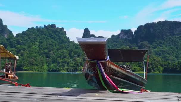 Egy gyönyörű longtail hajóval parkol a dokk a tavon. — Stock videók