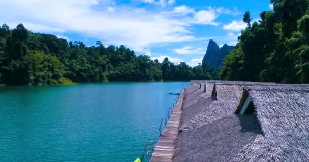 Aérea: techos de paja bungalows están de pie en un lago. Kayaks . — Vídeos de Stock