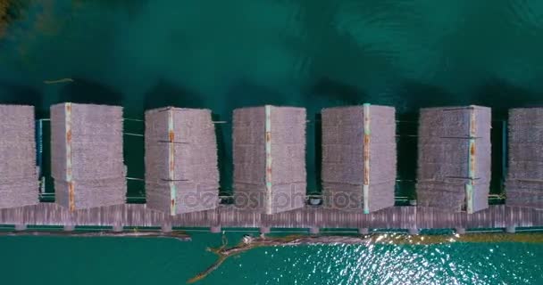 Aerial: Several thatched roofs floating houses are standing on the lake. — Stock Video