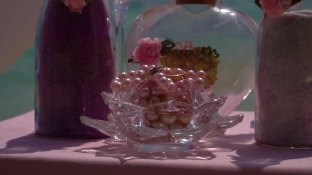 婚戒和酒杯在海边的桌子上。婚庆装饰. — 图库视频影像