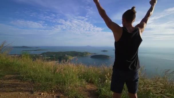 Sportovní mladý muž stojí s rukama na okraji hory. — Stock video