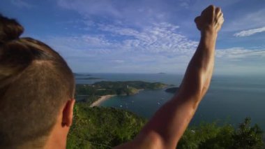 Atletik genç adam elleriyle dağ kenarında ayağa kalkar.
