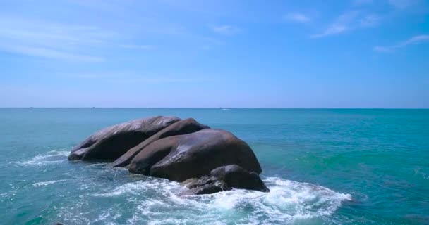 Aérea: Las olas se lavan y chocan contra una gran roca en el mar . — Vídeos de Stock