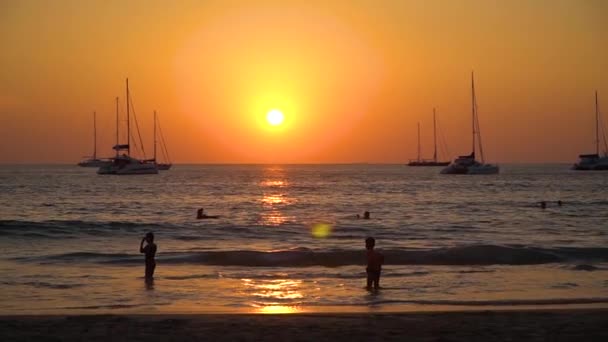 Dzieci kąpać się w morzu o zachodzie słońca. Statki na horyzoncie. — Wideo stockowe