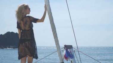 Sarışın gemi yay üzerinde duruyor ve denizde görünüyor.