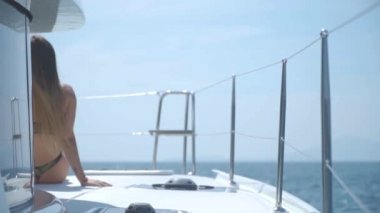 Genç bir kız bir gemi güvertesinde oturan.