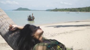 Yeşil giysili bir Asyalı kız dinlenme, rahatlatıcı bir palmiye ağacı üzerinde yalan söylüyor.