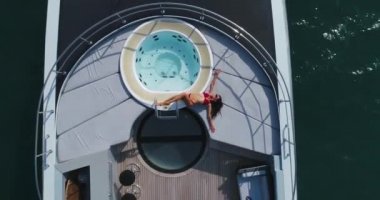 Hava: Kız yatıyor ve jakuzi yakınındaki yat güvertede sunbathes.