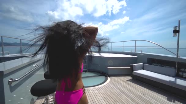 An Asian girl in a pink swimsuit goes and sits in a jacuzzi on a luxury yacht. — Stock Video