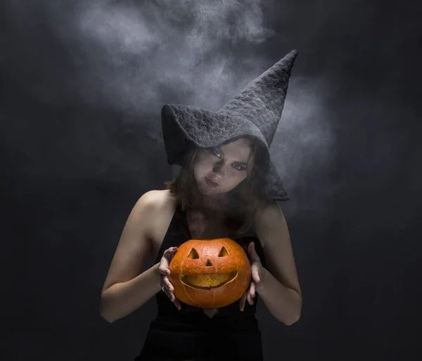 Angry witch with smoky pumpkin in her hands