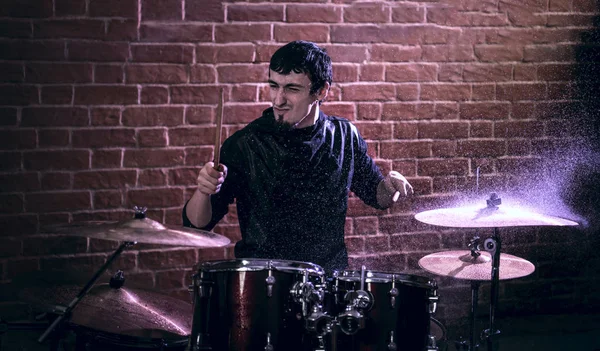 Portrait of emotional drummer rehearsing on drums before rock concert