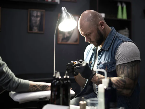 male tattooist preparing  filling machine for work with client i