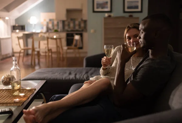 Multiethnic couple relaxing on couch with wine