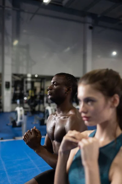 Sportive man and woman exercising together in gym