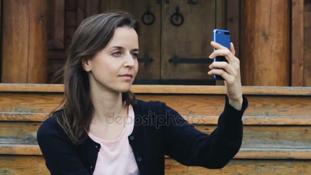 Красивая молодая девушка улыбается, чтобы сделать селфи на мобильном — стоковое видео